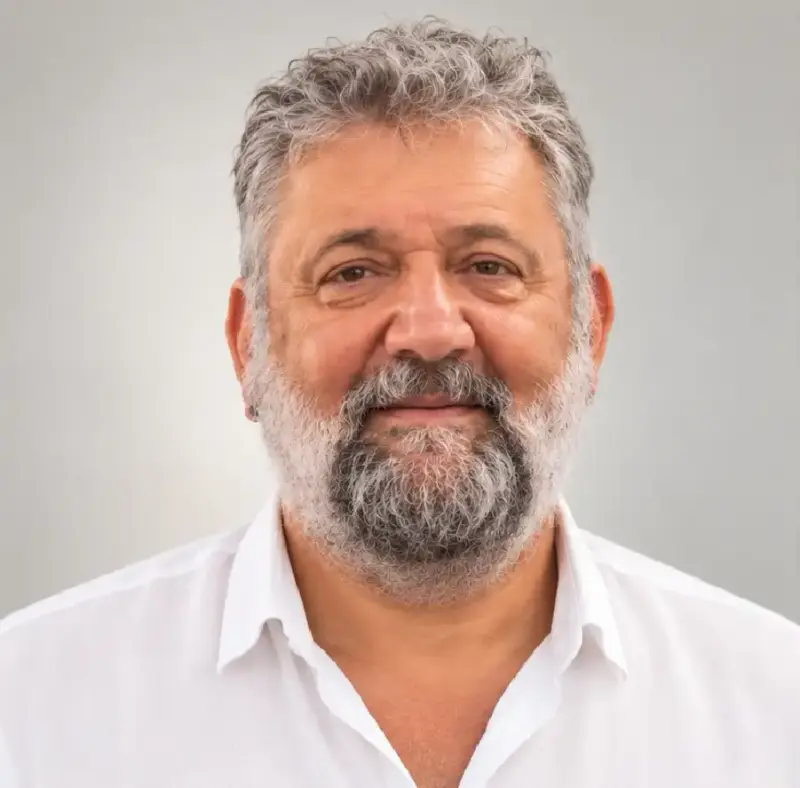 Retrato de Abel Figgini, de barba canosa y camisa blanca, sobre fondo gris claro.